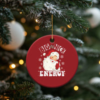 Red round Santa Christmas ornament with “Big Nick Energy” graphic, hanging from tree branch