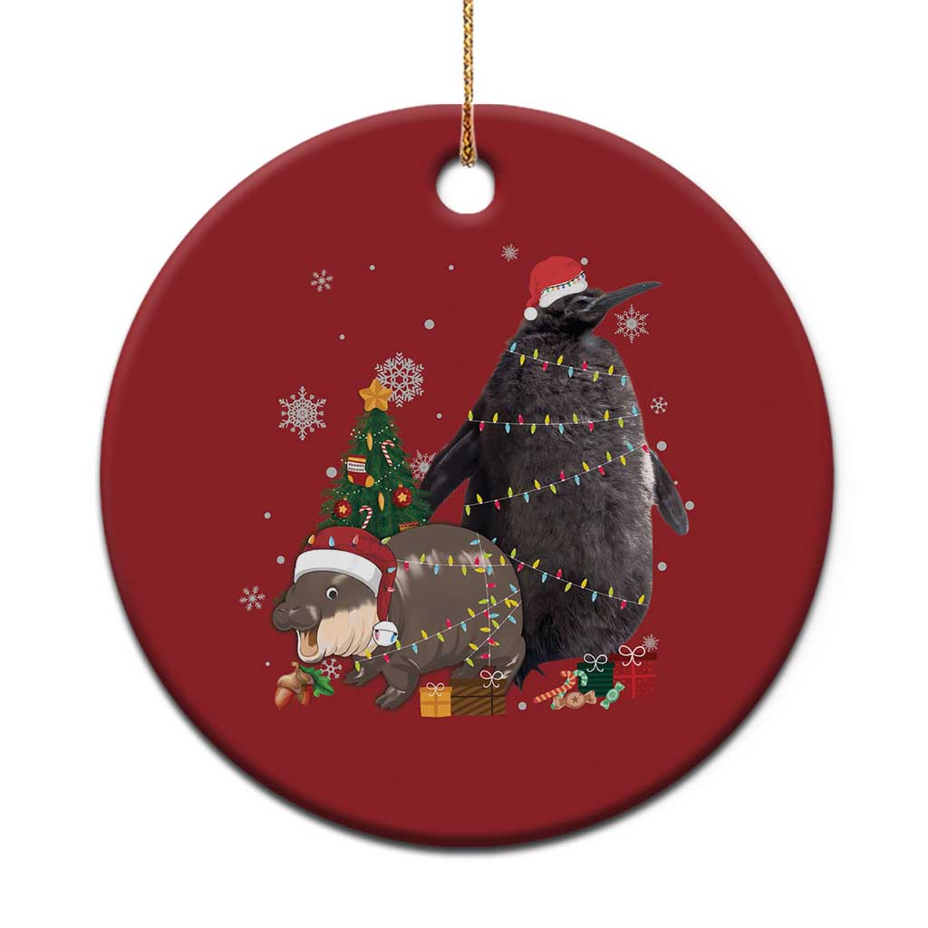 Red round Christmas ornament with a penguin, small hippo, Santa hat, and gifts design