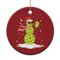 Red round Christmas ornament with a cartoon snowman holding a paddle, gold hanging loop