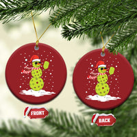 Two red round Christmas ornaments with cartoon snowman holding a paddle, gold hooks, front/back tags