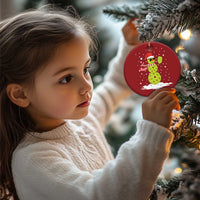 Red round Christmas ornament on a tree, with cartoon snowman holding a paddle
