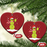 Two red heart-shaped ornaments with cartoon snowman holding a paddle, gold hooks, front/back tags