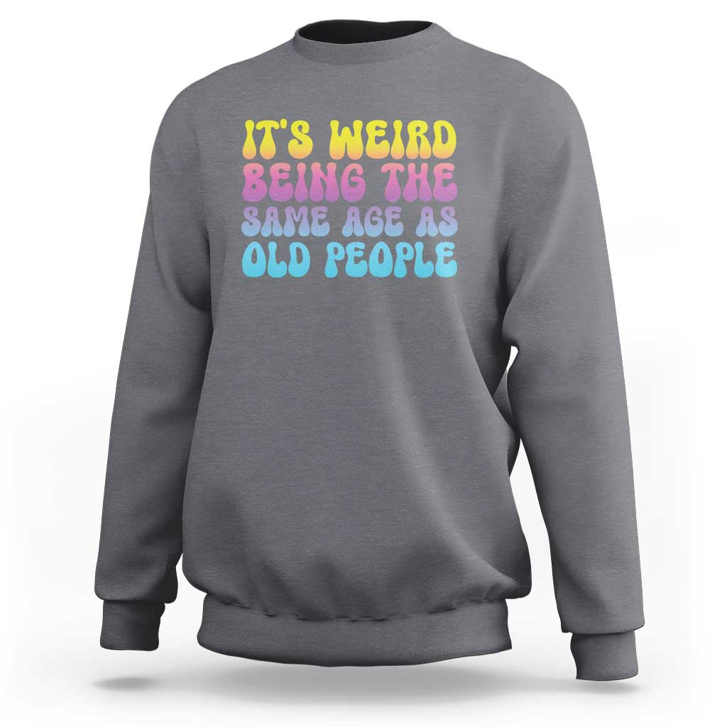 Charcoal gray crewneck sweatshirt with multicolor 'It's weird' and 'old people' text graphic