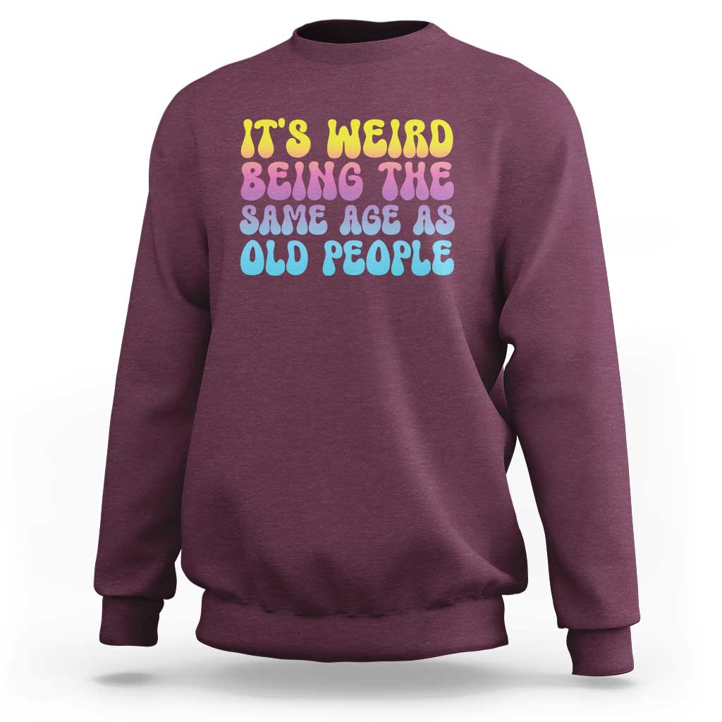 Maroon crewneck sweatshirt with multicolor 'It's weird' and 'old people' text graphic
