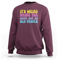 Maroon crewneck sweatshirt with multicolor 'It's weird' and 'old people' text graphic