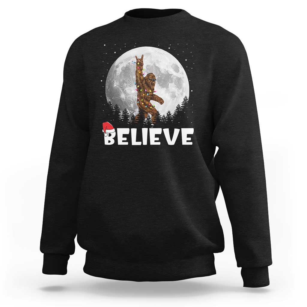 Black Christmas sweatshirt with Bigfoot 'BELIEVE' graphic under full moon.