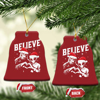 Red bell-shaped ornament set with “BELIEVE” and alien and Bigfoot graphics