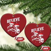 Two red heart-shaped “BELIEVE” ornaments with alien and Bigfoot graphics