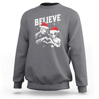 Charcoal crewneck sweatshirt with 'Believe' alien and Bigfoot graphic