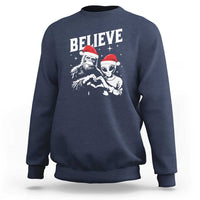 Navy crewneck sweatshirt with 'Believe' alien and Bigfoot holiday graphic