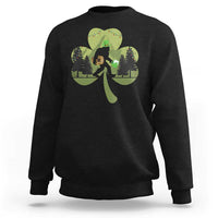 Black sweatshirt with Bigfoot graphic holding a green shamrock and clover leaves