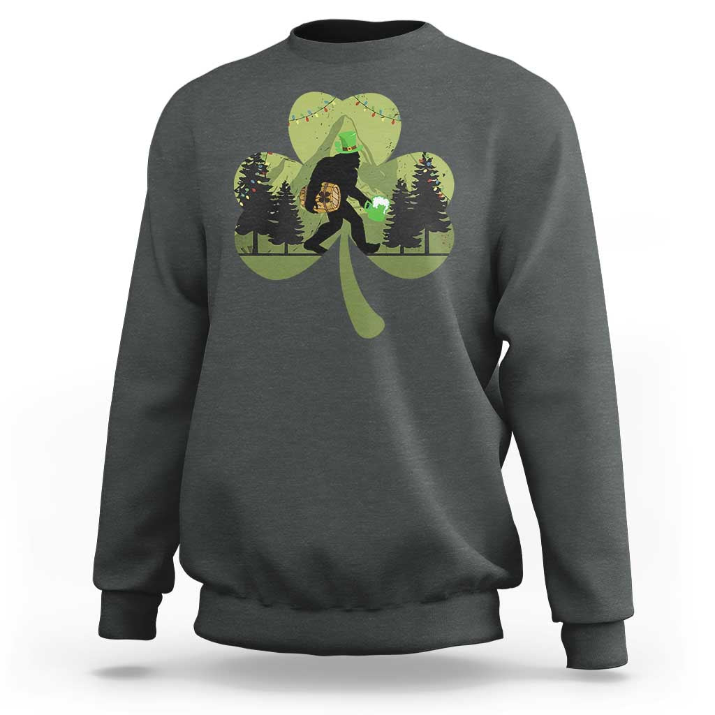 Dark heather sweatshirt with Bigfoot graphic holding a green shamrock and clover leaves
