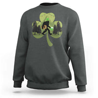 Dark heather sweatshirt with Bigfoot graphic holding a green shamrock and clover leaves