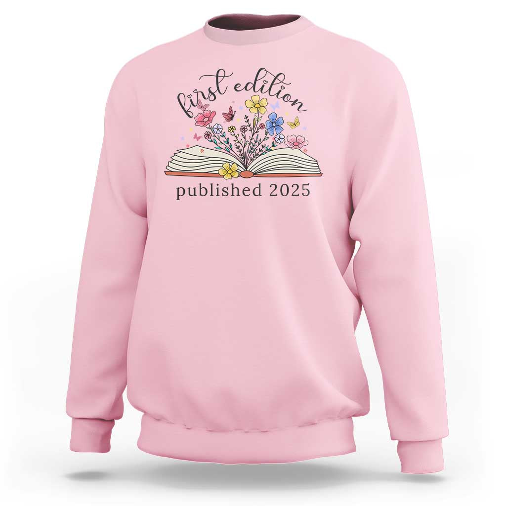 Light pink crewneck sweatshirt with floral book stack and “published 2025” front print.
