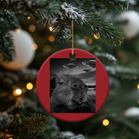 Red round capybara selfie Christmas ornament with UFOs, gold loop attachment on top.