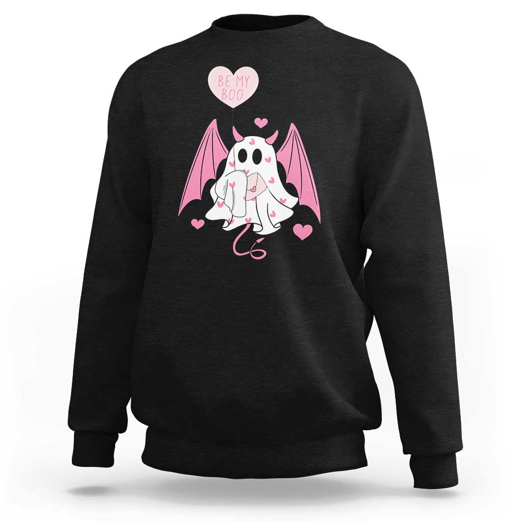 Black crewneck sweatshirt with pink bat-winged ghost holding a heart and text