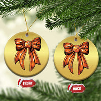 Two gold round Christmas ornaments with orange bow artwork, each with a hanging loop