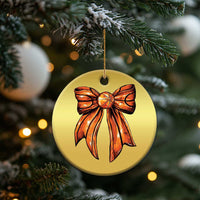 Gold round Christmas ornament featuring an orange ribbon bow and gold hanging cord