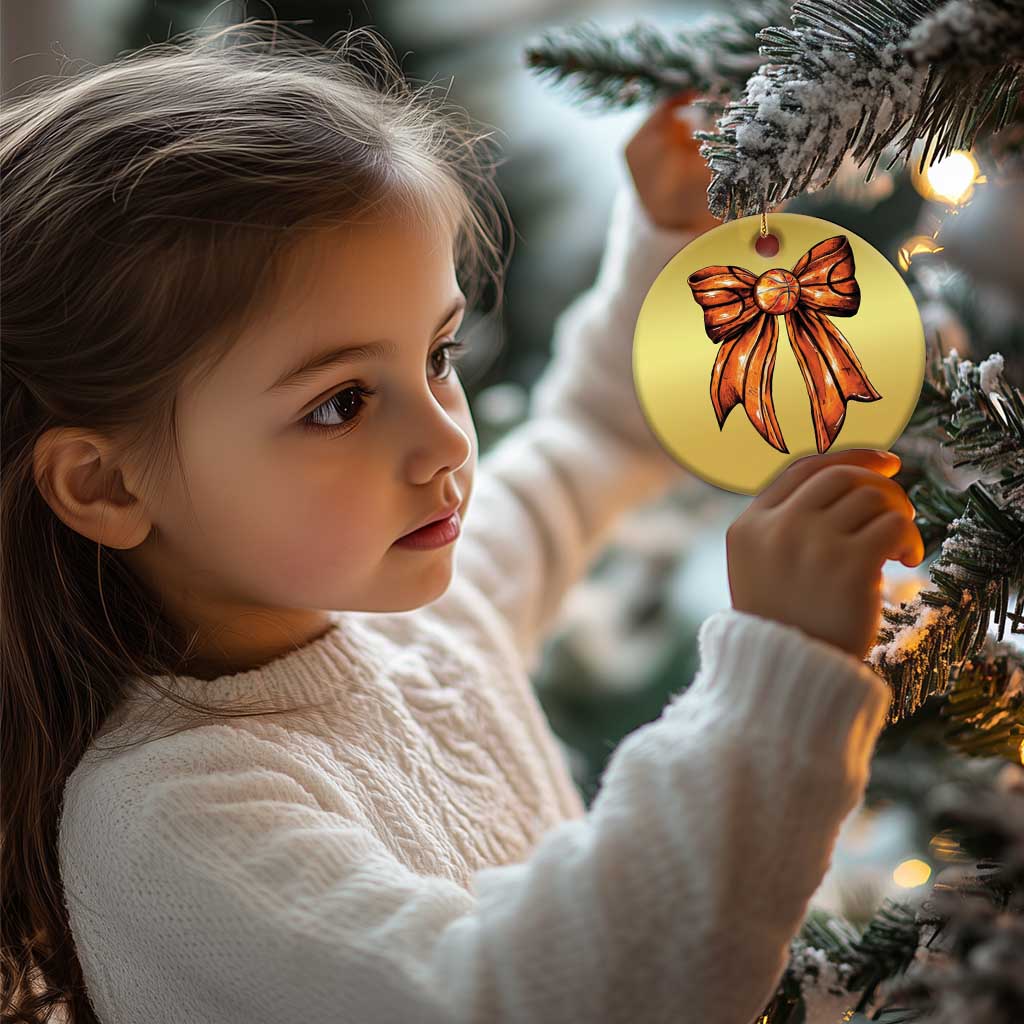 Gold round Christmas ornament with orange bow illustration, hanging from a gold cord