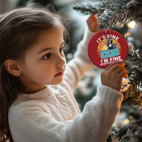 Child holding a red round raccoon noodle cup Christmas ornament with “It’s Fine, I’m Fine”