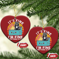 Two hanging red heart ornaments featuring a raccoon with a noodle cup, “It’s Fine” text