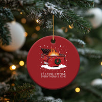 Red round Christmas ornament hanging on a gold string with flaming cart graphic and text