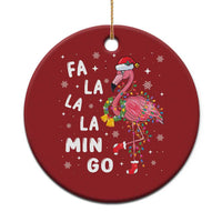 Red round flamingo Christmas ornament with hanging gold string and “FA LA LA MIN GO” text.