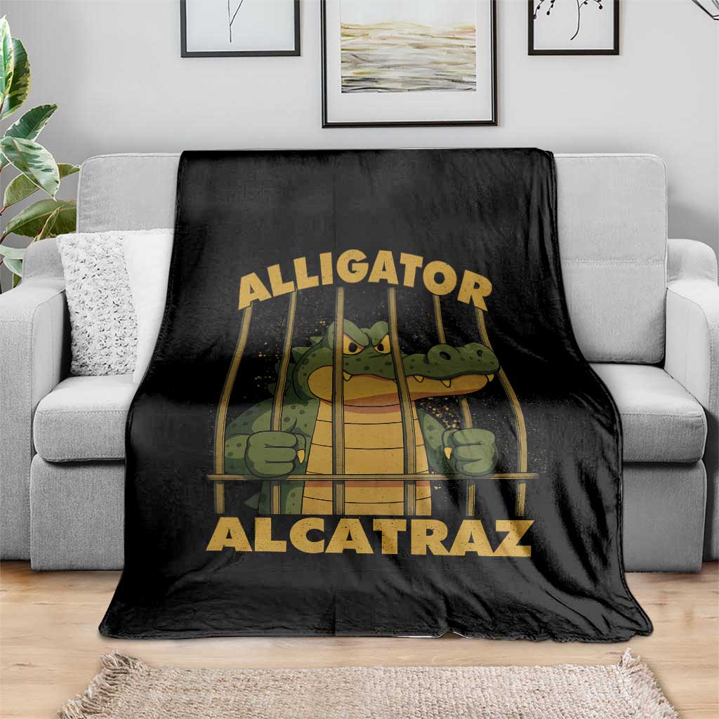 Black throw blanket with alligator-in-prison bars graphic, spread over gray sofa