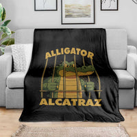 Black throw blanket with alligator-in-prison bars graphic, spread over gray sofa