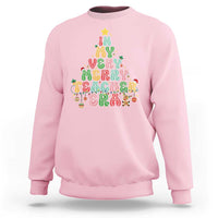 Light pink teacher sweatshirt with colorful “Merry Teacher” holiday graphic on front.