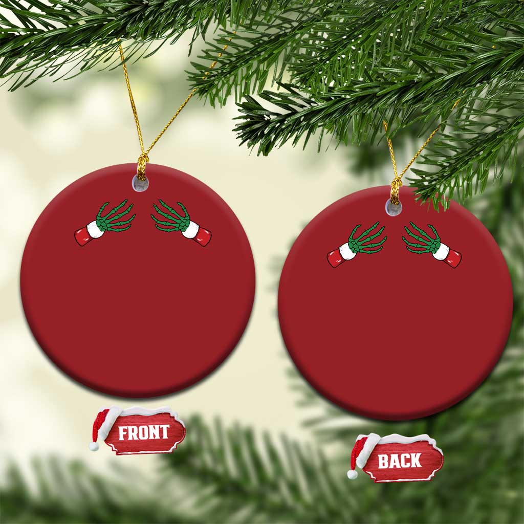 Two red circular Christmas ornaments on a tree branch with green skeleton hand design