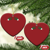 Two red heart-shaped Christmas ornaments with green skeleton hands and gold hanging loops