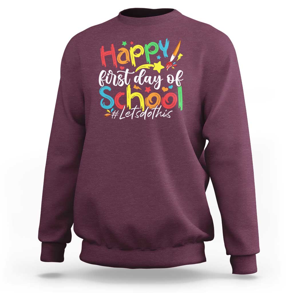 Maroon crewneck sweatshirt with “Happy first day of school” colorful graphic text
