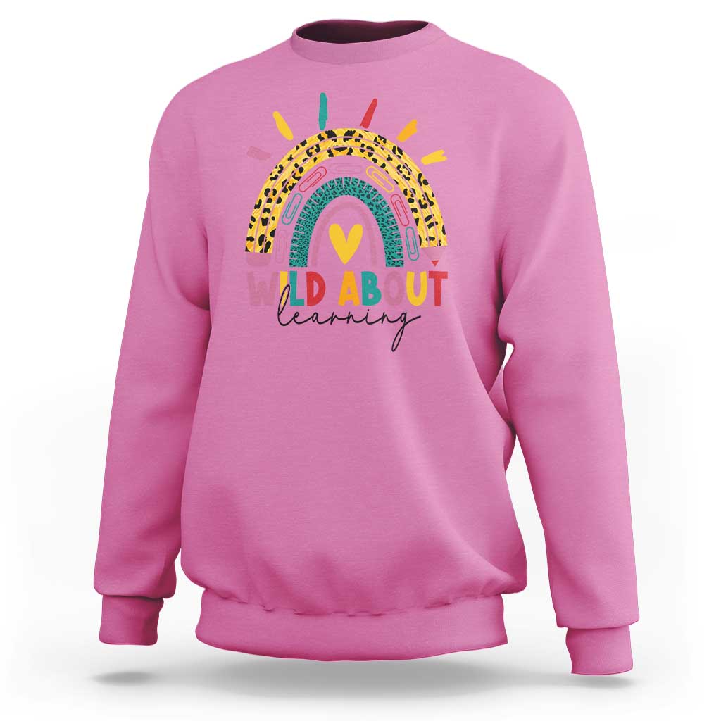 Rose pink back-to-school sweatshirt with rainbow leopard graphic and “WILD ABOUT learning” text