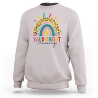 Light gray back-to-school sweatshirt with rainbow leopard graphic and “WILD ABOUT learning” text