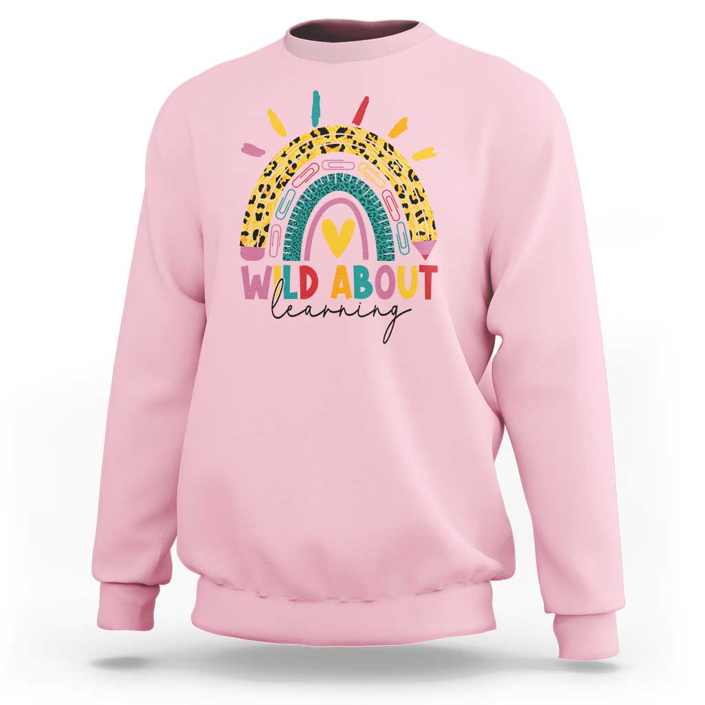 Light pink back-to-school sweatshirt with rainbow leopard graphic and “WILD ABOUT learning” text