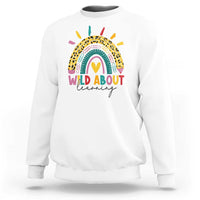 White back-to-school sweatshirt with rainbow leopard graphic and “WILD ABOUT learning” text
