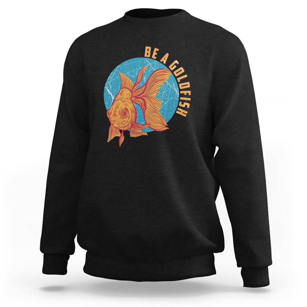 Black sweatshirt with goldfish graphic and vertical text "BE A GOLDFISH" on chest