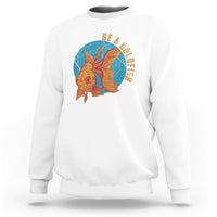 White sweatshirt with goldfish graphic and vertical text "BE A GOLDFISH" on chest