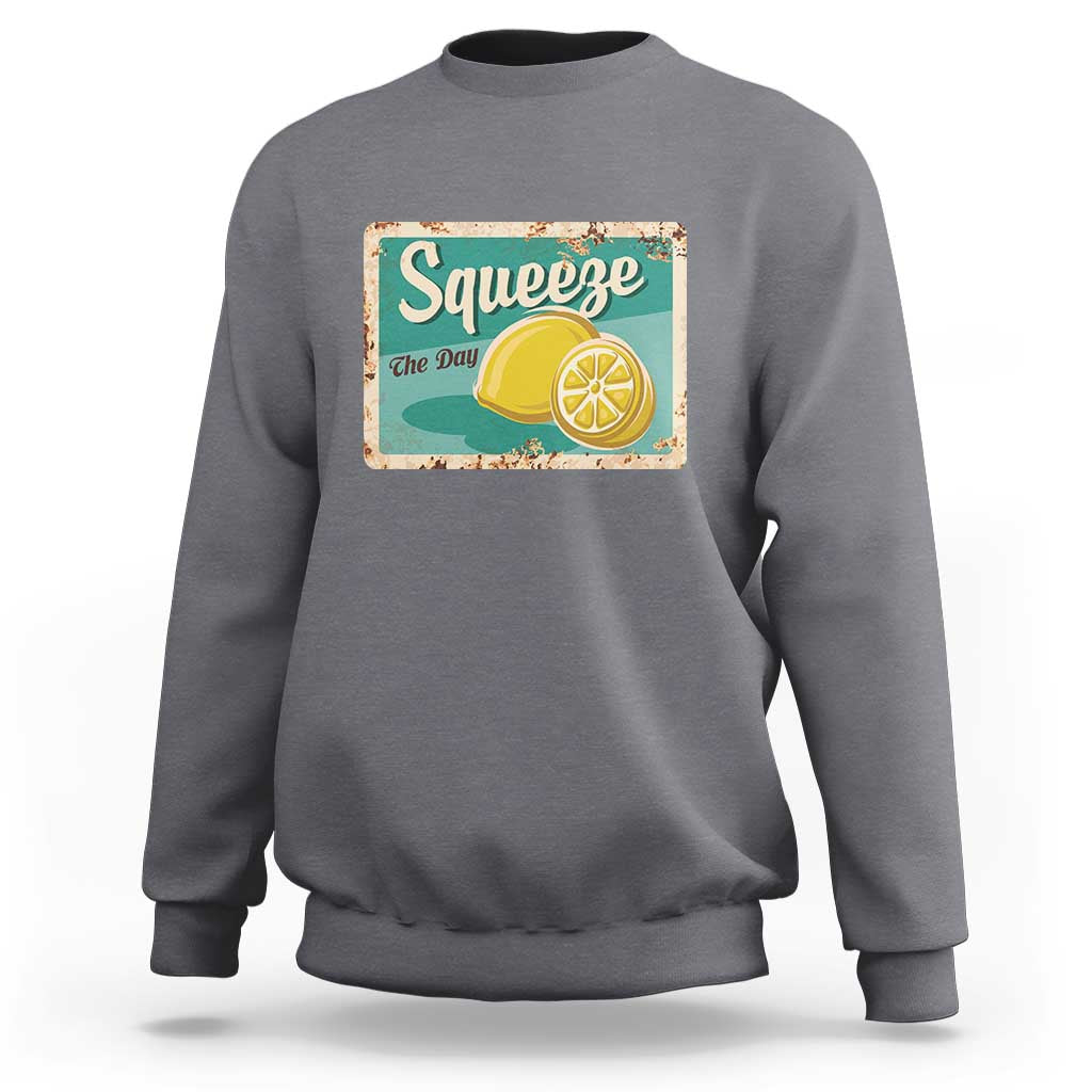Gray crewneck sweatshirt with front “Squeeze the Day” lemon graphic