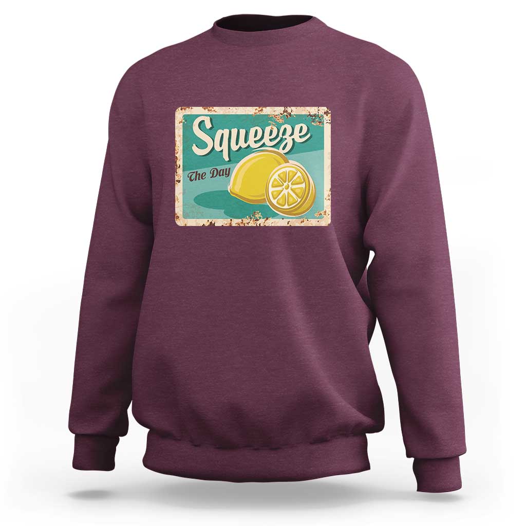 Maroon crewneck sweatshirt with front “Squeeze the Day” lemon graphic