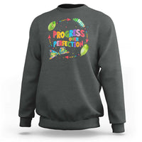 Dark gray sweatshirt with front graphic text "PROGRESS OVER PERFECTION" and colorful leaves
