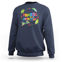 Dark blue sweatshirt with front graphic text "PROGRESS OVER PERFECTION" and colorful leaves