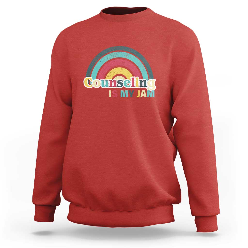 Red sweatshirt with ribbed crew neck and front rainbow “Counseling Is My Jam” graphic