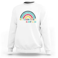 White sweatshirt with ribbed crew neck and front rainbow “Counseling Is My Jam” graphic