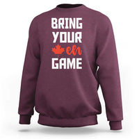 Maroon sweatshirt with “BRING YOUR EH GAME” text and orange maple leaf graphic