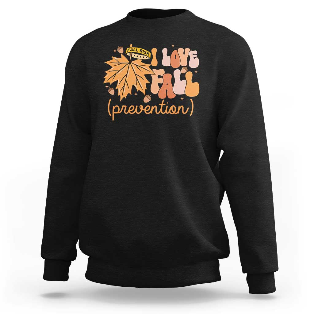 Black crewneck sweatshirt with “Love Fall (prevention)” autumn leaf graphic, long sleeves.
