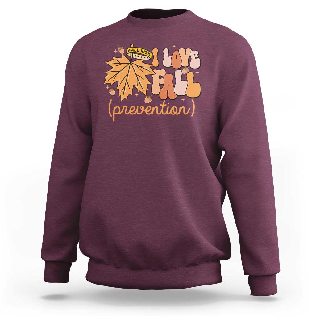 Maroon crewneck sweatshirt with “Love Fall (prevention)” autumn leaf graphic, long sleeves.