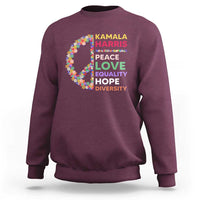 Maroon crewneck sweatshirt with colorful floral peace sign and “KAMALA HARRIS” text