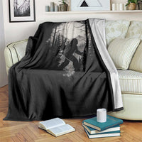 Black throw blanket with Bigfoot hiker forest print on a couch